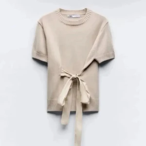 Beige stickad topp med knyt från Zara - Superfin beige stickad topp från Zara med korta ärmar och snygg knytning i midjan. Perfekt för dig som gillar en enkel men trendig look. Ribbad kant vid hals, ärmslut och nederkant ger en extra touch. Stl m men passar mig med xxs-s då den är jätteliten i storleken. Super bra skick💕