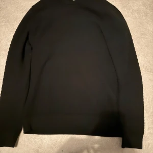 Svart ribbad tröja Jack & Jones - Svart långärmad tröja från Jack & Jones med ribbad struktur. Enkel och stilren design, perfekt till jeans eller chinos. Mjuk och skön känsla, rund halsringning och normal passform.