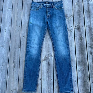 Blå jeans från Neuw - Säljer ett par klassiska blå jeans från Neuw med snygg slitning och femficksdesign. Jeansen sitter som slim men är en skinny modell. Jeansen har normal midja, smal passform och är tillverkade i mjukt bomullstyg med lite stretch. Perfekta för dig som gillar en stilren och modern look.