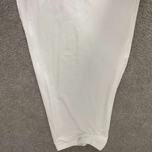 Vit långkjol med slits - Säljer en stilren vit långkjol med slits på sidan. Kjol har en rak och enkel siluett, perfekt för dig som gillar minimalistisk design. Materialet känns mjukt och lätt mot huden, vilket gör den skön att bära under varma dagar.