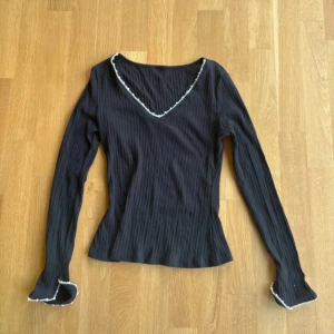 Svart ribbad topp med pärldetaljer - Fin långärmad tröja med pärldetaljer från Shein. Aldrig använd förut. Ärmarna har en liten slits. Lappen är borta men det är storlek xs. Tröjan är ribbad i tyget. 