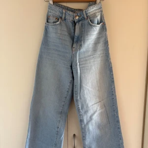 Ljusblå wide jeans med hög midja - Säljer ett par ljusblå jeans med breda ben och hög midja. Klassisk femficksmodell med knapp och dragkedja framtill. Jeansen har en chill och avslappnad vibe, perfekta för dig som gillar loose fit och retrostil. Materialet är jeans i bomull.