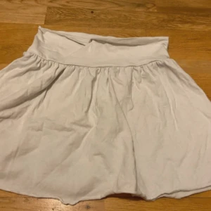 Vit kortkjol med bred midja - Säljer en vit kortkjol med bred, mjuk midja och lätt utställd form. Kjolen är tillverkad i bomull och har en enkel, stilren look utan mönster eller detaljer. Perfekt för dig som gillar en clean och chill stil.