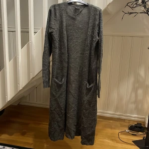 Grå lång kofta från VILA - Säljer en lång och mysig grå kofta från VILA i storlek M. Koftan har två praktiska fickor framtill, långärmad design och är tillverkad i ett mjukt stickat material. Perfekt att slänga över en t-shirt eller hoodie när det är kyligt ute. 99kr frakt inte inklusive.