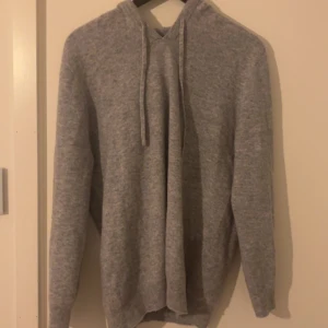 Kashmir hoodie - Mjuk och enkel grå hoodie med huva och snörning framtill. Tröjan har långärmade ärmar och en loose passform som gör den skön att bära. Perfekt för chill dagar eller när du vill ha något bekvämt. Materialet är Kashmir. Passar L också