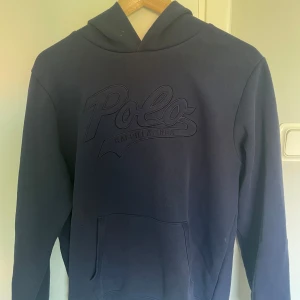 Mörkblå hoodie från Polo Ralph Lauren - Säljer en mörkblå hoodie från Polo Ralph Lauren, passar storleken S perfekt men passar även M. Tröjan har ett stort broderat Polo Ralph Lauren-tryck på bröstet. Materialet är mjuk bomull och passformen är normal.                                                                                  Tveka inte att fråga om mer bilder!                    Pris kan diskuteras!