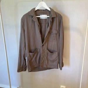 Brun overshirt från A Day's March - Snygg brun overshirt från A Day's March i storlek S. Jackan har klassisk krage, stora fickor framtill och en knappstängning. 
