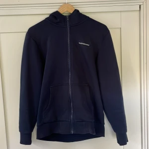 Mörkblå hoodie från Peak Performance - Säljer en mörkblå hoodie med huva och full zip från Peak Performance i storlek S. Knappt använd 