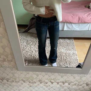 Mörkblå bootcut jeans med låg midja - Säljer ett par mörkblå jeans med snygg bootcut och låg midja. Jeansen har markerade sömmar, klassiska fickor fram och bak samt en lätt tvättad färg. Dock, var det ett hål vid skrevet, så jag har strukit fast en jeanslapp där på insidan. Så nu syns det inte💞