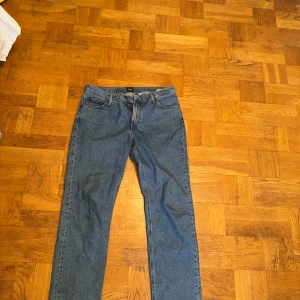 Blå raka jeans från Lee - Säljer ett par klassiska blå jeans från Lee med rak passform och normal midja. Nypris 1200kr. Bra skick. Storlek 34/32