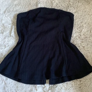Svart ribbad bandeu - Svart ribbad bandeu från Bikbok. Legat i min garderob ett tag. ”Slits” vid ryggen. Fin att ha till jeans t.ex😊Skriv gärna för fler bilder/info.