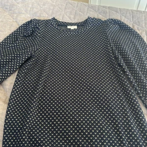 Mörkblå långärmad tröja med hjärtan - Supersöt mörkblå tröja från Stajl med små vita hjärtan över hela. Rund hals och långa ärmar, perfekt för dig som gillar gulliga detaljer. Materialet känns mjukt och skönt mot huden, och passformen är normal. En tröja som sticker ut med sitt fina mönster!