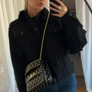 Svart jacka  med fransar - Säljer en svart javcka med coola fransdetaljer på axlar och ärmar. Jackan har knappar framtill och klassiska fickor på bröstet. Perfekt för hösten 🤩