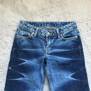 Weekday Nova Low Slim Bootcut Jeans - Säljer ett par Weekday Nova Low Slim Bootcut jeans i blå tvätt med coola slitningar och blekta detaljer längs benen. Modellen har låg midja och bootcut passform som ger en snygg siluett. Ni ser på sista bilden att dessa jeans har varit för långa för mig som 160 och därav har jag råkat trampa på dom när jag har gått men det är ingenting man lägger märke på när man ser bakifrån, storlek 23. Jeansen säljs inte längre och har varit svåra att få tag i. Nypris är 750 kr