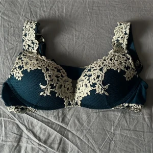 Intimissimi bh 75b - Supersnygg mörkblå korsett med krämvit broderad spets i blommigt mönster över kuporna och axelbanden. Materialet är mjukt och har en mesh-liknande struktur. Justerbara axelband och hakknäppning bak för perfekt passform. Perfekt för dig som gillar detaljer och romantisk vibe. Denna färg säljs inte längre💙
