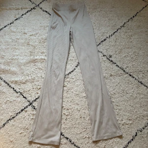 Beige ribbade bootcut-byxor H&M Divided - Snygga beige ribbade byxor från H&M Divided, modell med bootcut och hög midja. Materialet är mjukt och stretchigt, perfekt för en chill och trendig look. Smala ränder i tyget ger extra vibe. Passar dig som gillar bekvämt men ändå vill ha stil.