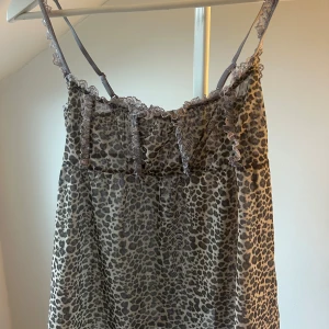 Leopardmönstrad topp med spets - Säljer en topp med leopardmönster och tunna axelband. Linnet har fina spetsdetaljer längs urringningen och är i en beige och brun färgskala. Perfekt för dig som gillar djurmönster och vill ha en unik look.