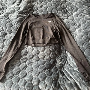 Gymshark croppad svart långärmad träningströja - Använd några fåtal gånger men i fint skick, bara att lappen är avklippt. Storlek S. Har hål längst ner på armarna för att kunna ha tummen där om man vill.