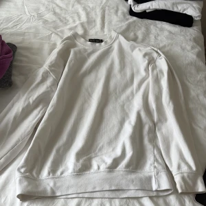 Vit sweatshirt från PrettyLittleThing - En stilren vit sweatshirt från PrettyLittleThing i storlek S. Tröjan har rund halsringning, långa ärmar och är gjord i mjuk bomull. Perfekt för en clean och avslappnad look. Passar till allt och är superenkel att matcha med jeans eller leggings.