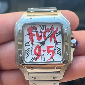 Seiko automatisk klocka med unik urtavla - Snygg Seiko klocka med automatisk urverk och en iögonfallande urtavla med texten 'FUCK 9-5'. Klockan har en fyrkantig boett i silverfärgat stål och romerska siffror. Armbandet är också i silverfärgat stål med en säker låsning. Perfekt för den som vill sticka ut!