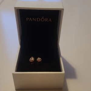 Droppformade örhängen från Pandora i roséguld - Säljer ett par droppformade örhängen från Pandora i roséguld med glittriga stenar. Perfekta för att ge en elegant touch till din stil. Kommer i originalask.