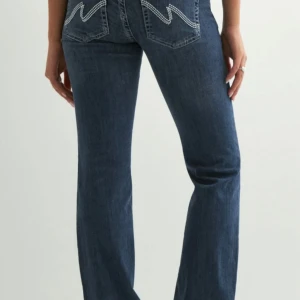Nelly Low Waist Bootcut Stitch Jeans - Säljer de populära jeansen från Nelly i storlek M, Low Waist Bootcut Stitch Jeans. Snygga mörkblå bootcut jeans från Nelly med  vit broderad W på bakfickorna. Jeansen har låg midja, dubbla knappar och klassisk femficksdesign. Tillverkade i stretchig denim. De är i nyskick då jag köpt fel storlek🩷