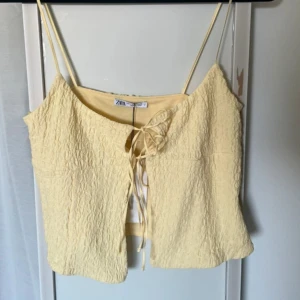 Gul linnetopp från Zara - Säljer en ljusgul linnetopp från Zara med tunna axelband och knytning framtill. Toppen har en lätt skrynklig struktur och är perfekt för varma dagar.💛💛💛