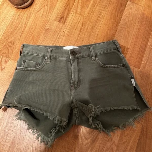 shorts från OneTeaspoon - Säljer ett par olivgröna shorts från OneTeaspoon med råa fransar längs kanterna och klassisk femficksdesign. Shortsen har låg midja och är tillverkade i ett kraftigare bomullsmaterial. Perfekta för sommaren!