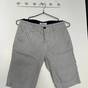 Randiga shorts från Hampton Republic - Snygga randiga shorts från Hampton Republic i vitt och blått. Klassisk passform med knapp och dragkedja framtill samt fickor både fram och bak. Perfekta för sommardagar och enkel att matcha med t-shirt eller skjorta.