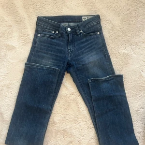 Mörkblå jeans från Crocker - Snygga mörkblå jeans från Crocker med klassisk femficksdesign och silverfärgade knappar. Jeansen har en rak passform och är tillverkade i slitstarkt denim. Perfekta för dig som gillar en tidlös och enkel stil.
