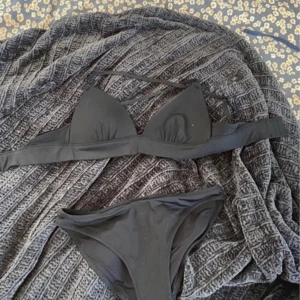 Svart bikini från H&M - Säljer en svart bikini från H&M med enkel och stilren design. Överdelen har triangelformade kupor och smala axelband, medan underdelen är klassisk med normal passform. Perfekt för stranden eller poolen.