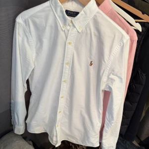 Vit skjorta från Polo Ralph Lauren - Klassisk vit skjorta från Polo Ralph Lauren i slim fit med button-down krage och broderad logga på bröstet. Skjortan är enbart använd 1 gång o e perfekt för en stilren look.