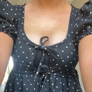 Svart prickig blus med puffärmar och knyt - Supersöt svart blus med vita prickar och puffärmar, perfekt topp nu inför sommaren🩷endast använd en gång