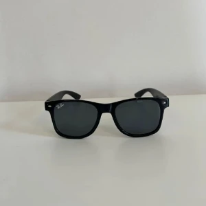 Ray-Ban Wayfarer solglasögon - Helt nya. Perfekta inför sommaren. Riktigt snygga och stilrena. Bågarna är 53 mm breda och 42 mm höga – perfekt för en cool look i solen. Extremt bra pris så först till kvarn😁 ingen text eller märke på bågarna därför ej äkta.