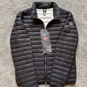 Svart dunjacka från Colmar - Snygg svart dunjacka från Colmar med quiltad design och dragkedja framtill. Jackan har en stilren ståkrage och insidan är ljusgrå. Perfekt för dig som vill ha en lätt och varm jacka med modern look. Colmar-logga på ärmen ger extra streetkänsla. Storlek L men passar som M mer 