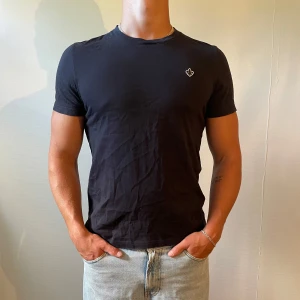 Morris t-shirt storlek S - Marinblå t-shirt med rund hals och korta ärmar. På bröstet finns en liten vit logga som detalj. T-shirten har en slim passform och är gjord i mjuk bomull, perfekt för en clean och enkel stil.