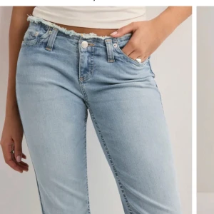 Ljusblå bootcut jeans med rå kant - Säljer ett par ljusblå jeans med bootcut-modell och rå, fransad midja. Jeansen har klassisk femficksdesign, normal passform och är tillverkade i mjukt denimtyg. Perfekta för en avslappnad och trendig look.