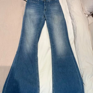 Blå bootcut jeans från Dondup - Snygga ljusblå bootcut jeans från Dondup, modell Janet. Jeansen har klassisk femficksdesign och en utsvängd siluett. Tillverkade i mjukt bomullsjenastyg med slitningar framtill för en cool vintagekänsla. Nypris 3000 kr.