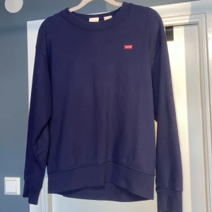 Levis tröja - En stilren mörkblå sweatshirt från Levi's i storlek XS. Tröjan har rund halsringning, långa ärmar och en liten röd Levi's-logga på bröstet. Tillverkad i mjuk bomull, perfekt för en chill och avslappnad look. Säljer för att den är för liten Mvh 