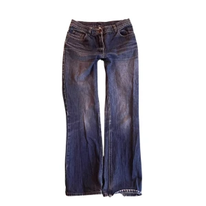 Blå bootcut jeans med slitningar - Snygga blå jeans med bootcut passform och coola slitningar längs benen. Klassisk femficksmodell med låg midja och dragkedja. Perfekta för en avslappnad och trendig look.