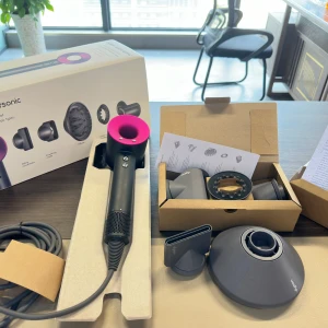 Dyson Supersonic hårfön med tillbehör - Säljer en svart och rosa Dyson Supersonic hårfön med flera stylingmunstycken och diffuser. Allt kommer i originalförpackning med tillbehör och manual. Perfekt för att snabbt torka och styla håret med proffsigt resultat.