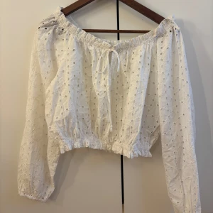 Vit offshoulder blus med broderi -  en vit offshoulder blus med broderade hålmönster 