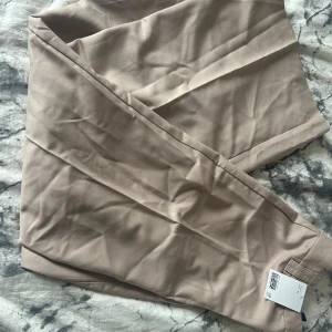 Beige wide kostymbyxor - Snygga beige kostymbyxor med wide fit och pressveck. Helt nya med prislapp, stl 34 men passar 36-38. Nytt pris 299kr