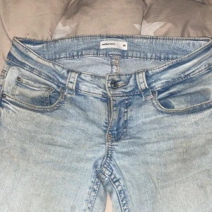 Bootcut ljusblå jeans från Perfect Jeans - Säljer ett par ljusblå bootcut jeans från Perfect Jeans. De har klassisk femficksdesign, knappstängning och bälteshällor. Jeansen är tillverkade i jeansmaterial och har snygga slitningar och kontrastsömmar. Perfekt för dig som gillar retrovibbar och avslappnad stil.