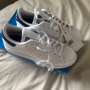 Adidas skor  - Vita stan smith med blåa detaljer, passar perfekt till vardagen storlek 38. Inte använda endast testad säljer då de va fel storlek🙌🏼 