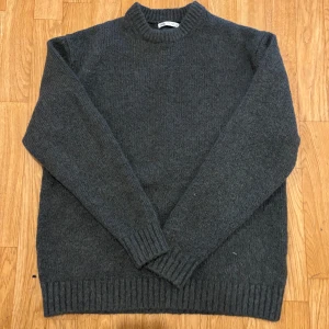 Mörkgrå stickad tröja från Zara - Mysig mörkgrå stickad tröja från Zara med rund halsringning och ribbade muddar vid ärmslut och nederkant. Perfekt för lager-på-lager och chill dagar. Klassisk modell som funkar till det mesta.