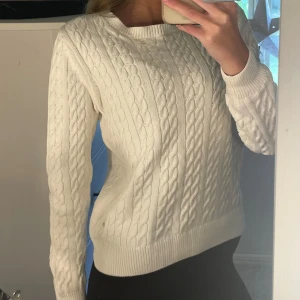 Vit kabelstickad tröja Holly & Whyte - Kabelstickad vit tröja från Holly & Whyte by Lindex. Klassisk modell med rund halsringning och ribbade muddar. Perfekt för lager-på-lager och passar till allt. Mjuk och skön känsla i bomullsmaterial. Använd enstaka gång.