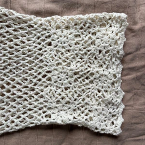 Vit virkad klänning med fransar - Säljer en vit, virkad ärmlös topp/klänning med  blommönster och långa fransar i ändarna. Unik och går att styla på många sätt! Över ett par jeans eller shorts blir supersnyggt!