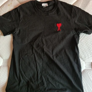 Ami Paris T-shirt  - En svart ami Paris T-shirt som säljs då den inte passar mig i storlek. Tröjan är i bra skick och används med hänsyn. Priset kan diskuters, vid eventuella frågor är de bara att skriva till. 