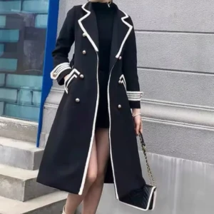 Svart kappa med vita detaljer - Stilren svart kappa med vita kontrastkanter och dekorativa guldknappar. Lång modell med markerad krage, dubbla rader knappar och snygga fickdetaljer. Ärmarna har vita ränder och kappan har en klassisk, elegant look. Perfekt för dig som vill sticka ut.